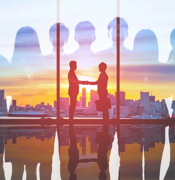 People shaking hands in front of window with city scape behind them
